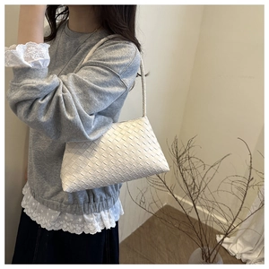 Close-up of white woven leather shoulder bag with minimalist trapezoid design