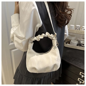 Detail of white pleated cloud bag with textured leather strap shown on shoulder