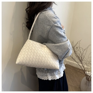 Detailed close-up of a white woven shoulder bag with intricate cross-weave pattern and texture