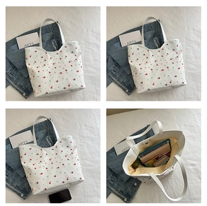 Detail of white canvas tote bag with strawberry prints, magnetic closure, and roomy interior