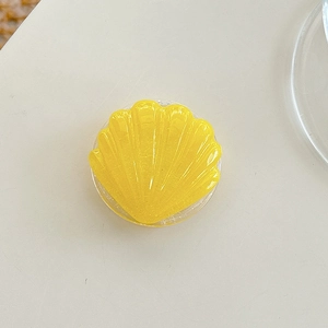 Macro shot of a yellow shell-shaped collapsible phone grip with glossy resin texture