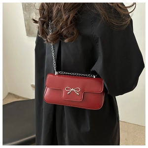 Macro detail of red PU leather bag with silver metal bow and fine chain strap