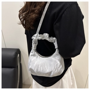Detail of silver crinkled shoulder bag featuring ruffled handle and sleek metallic texture