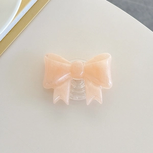 Macro detail of peach pink glitter bow phone grip with clear retractable base stand