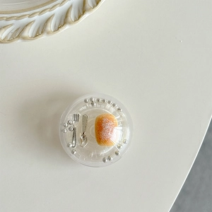 Macro view of clear sphere griptok featuring miniature bread, fork and spoon inside
