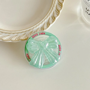 Macro view of green bow magnetic phone grip with Good Luck text on the base