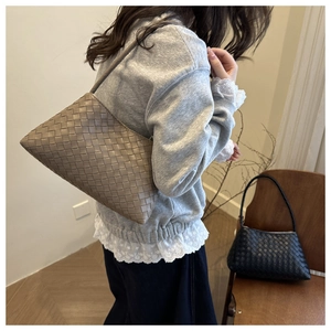 Detail of woven leather baguette shoulder bag showing texture and stylish underarm carry