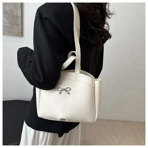Detailaufnahme der cremefarbenen Ledertasche mit silberner Schleife an einem Modell