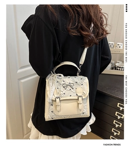 Back view of cream lace crossbody bag with black bows and pearl chain detail
