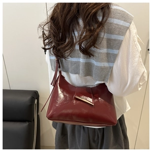 Burgundy patent leather shoulder bag with gold geometric buckle and tassel detail