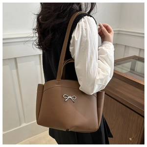 Detail einer braunen Ledertasche mit silberner Metallschleife und verstellbarem Riemen