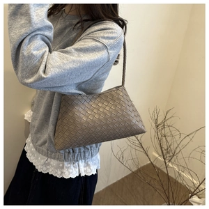 Macro detail of high-quality woven leather texture on a taupe baguette shoulder bag