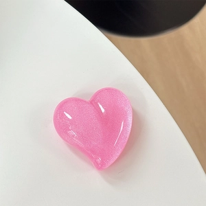 Detail of pink glitter heart phone grip accessory with shimmering iridescent resin finish
