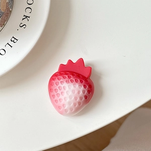 Detail of 3D resin strawberry phone grip with textured seeds on a white surface
