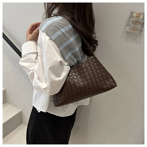 Detail of dark brown woven leather texture on a minimalist chic shoulder bag for women