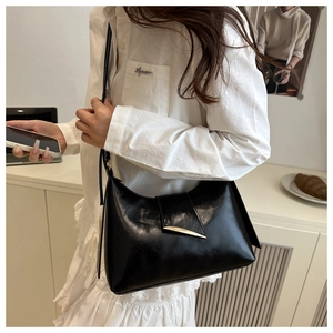 Detail view of black underarm bag featuring a golden crescent-shaped metal buckle