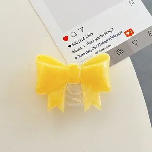 Macro shot of yellow glitter resin bow phone grip showing sparkling details and texture