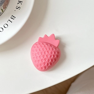 Macro detail of a 3D pink silicone strawberry phone grip with realistic seed texture