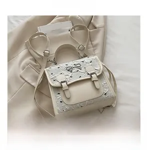 Detail of cream white backpack with black bow embroidery and metal bow buckle on a blazer