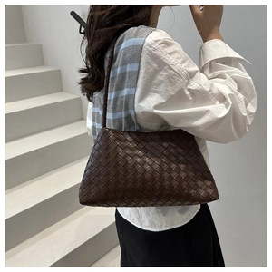 Detailed view of dark brown woven leather shoulder bag texture on a fashion model
