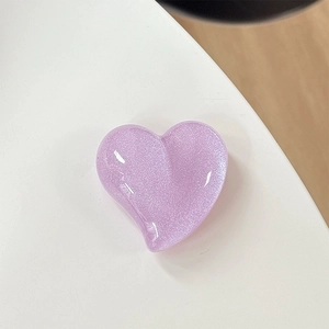 Macro shot of glittery heart-shaped phone grip accessory in light purple pearlescent finish