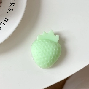 Macro detail of a 3D light green resin strawberry phone grip with realistic textured pits