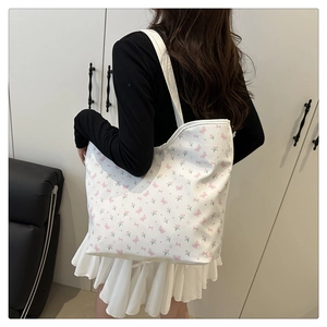 Close-up of white tote bag with tulip and butterfly floral print on canvas fabric