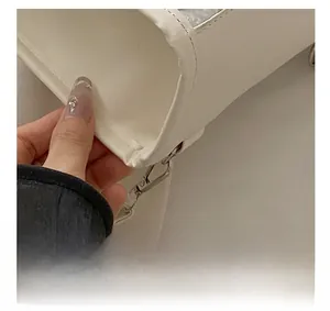Detailed close-up of the metal D-ring buckle and PU leather texture on a white backpack