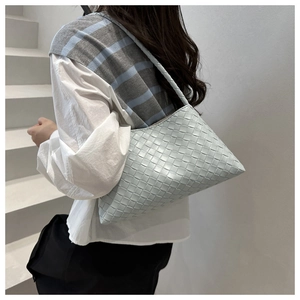 Detail of light blue woven rectangular shoulder bag featuring premium leather texture
