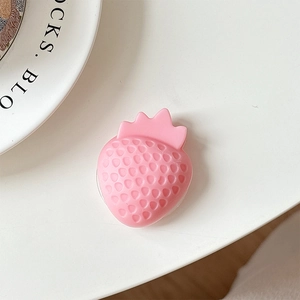 Macro view of a 3D pink strawberry phone grip with textured seeds on a white background