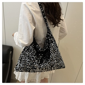Gros plan du sac fourre-tout à paillettes noires porté sur une tenue blanche