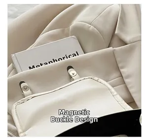 Detail of a creamy leather bag featuring a functional magnetic closure and fine stitching