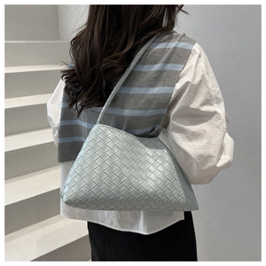 Close-up of woven mint green hobo bag with intricate leather texture on model shoulder