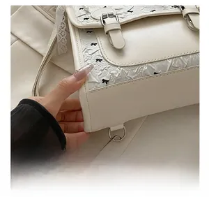 Detail shot of exquisite lace trim and black bow on a minimalist cream square bag