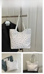 Detail of white tote bag featuring purple floral and bow print with synthetic leather handles