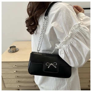 Detail of silver metal bow buckle on a black leather chic underarm shoulder bag