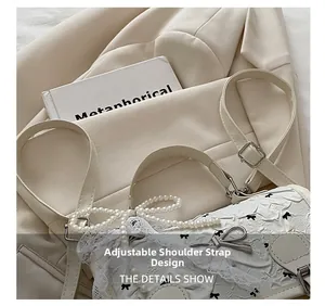 Close-up of adjustable strap design and pearl bow ornament on a lace crossbody bag