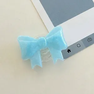 Detail view of a light blue bow phone grip with glitter resin finish on a retractable base