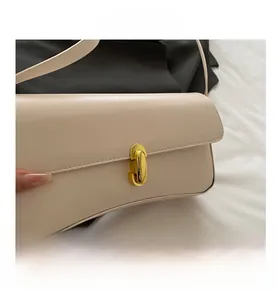 Detailed close-up of the elegant gold oval metal clasp on the beige leather handbag