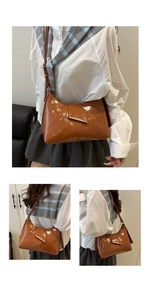 Close-up of a brown patent leather shoulder bag featuring a geometric metal buckle