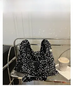 Détail du cabas à paillettes argentées montrant la texture brillante sur un support en métal