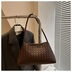 Close-up of dark brown woven leather texture and trapezoid structure of the shoulder bag