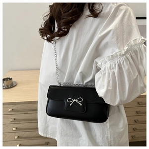 Détail du sac bandoulière noir avec nœud en métal argenté et fine bandoulière chaîne