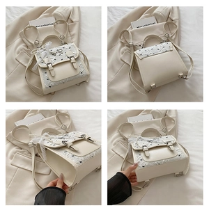 Detail view of cream backpack showing lace layers, black bows, and pearl charms