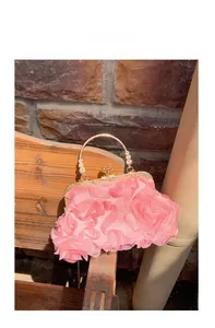 Detailed macro shot of 3D pink fabric roses and gold ring handle on evening clutch