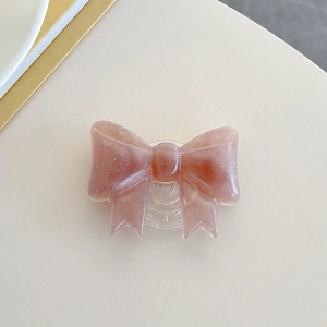 Detailed view of pink glitter bow phone grip with a transparent expandable base stand