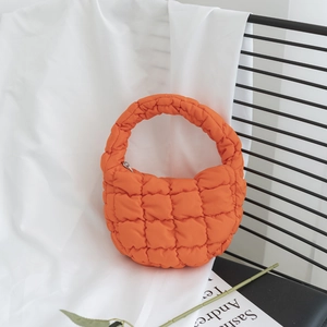 Gros plan sur un sac bouffant orange vif matelassé avec motif carré et poignée ronde