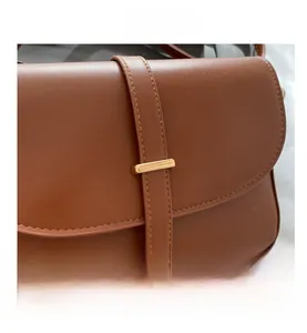 Dettaglio in pelle marrone con cuciture precise e chiusura in metallo dorato sulla borsa