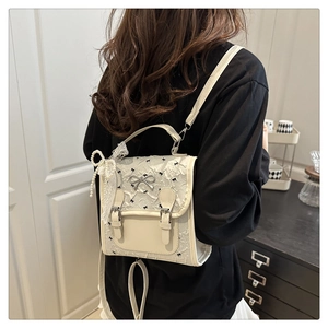 Detail of lace embroidery backpack with 3D floral accents and silver bow buckle
