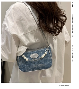 Detail der blauen Denim Baguette Tasche mit weißen Punkten und Perlenblumenkette